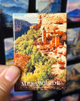 A hand holding a magnet with a picture of the mesa verde, a famous landmark in the Grand Canyon National Park.