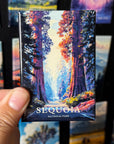 A hand holding a magnet with a colorful image of a forest, specifically depicting a scenic view of Sequoia National Park.