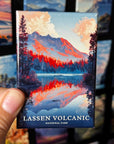 A hand holding a magnet with a landscape depicting a mountain and a lake, with the text "LASSEN VOLCANIC NATIONAL PARK".