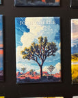 a large magnet with a painting of a Joshua tree in a desert landscape.