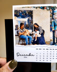 A person is holding a small photo frame containing a family portrait of a man, woman, and child sitting on a bench.