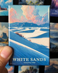 A hand holding a magnet with a landscape image of the White Sands National Park.