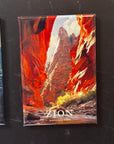 A magnet depicting a scenic view of the canyon of Zion National Park, with towering red rock formations and a bright sky.