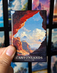 A hand holding a magnet with a picture of a canyon landscape, with the text "CANYONLANDS NATIONAL PARK" visible.