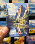 A hand is holding a magnet with a scenic image of the Kings Canyon National Park, featuring a mountain landscape with a lake and trees.