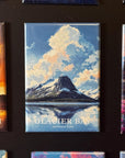 a collection of magnets depicting various landscapes, including a mountain range, a lake, and a sunset. The magnets are arranged in a row, showcasing the beauty of these natural scenes.