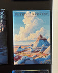 a large magnet with a painting of a forest landscape, including mountains, trees, and a cloudy sky.