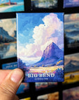 A hand holding a magnet with a landscape scene depicting a mountain and clouds, with the text "BIG BEND NATIONAL PARK" printed on it.