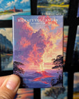 A hand holding a magnet with a colorful illustration of a Hawaiian volcano, with the text "HAWAII' VOLCANOES NATIONAL PARK" printed on it.