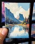 A hand holding a magnet with a painting of the Great Basin National Park, featuring mountains, trees, and a river.
