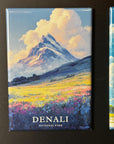 The image is a framed magnet depicting a scenic landscape with a snow-capped mountain, a field of flowers, and a cloudy sky.