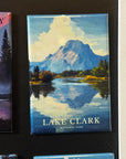 A magnet depicting Lake Clark National Park, with a mountain landscape and a lake in the foreground.