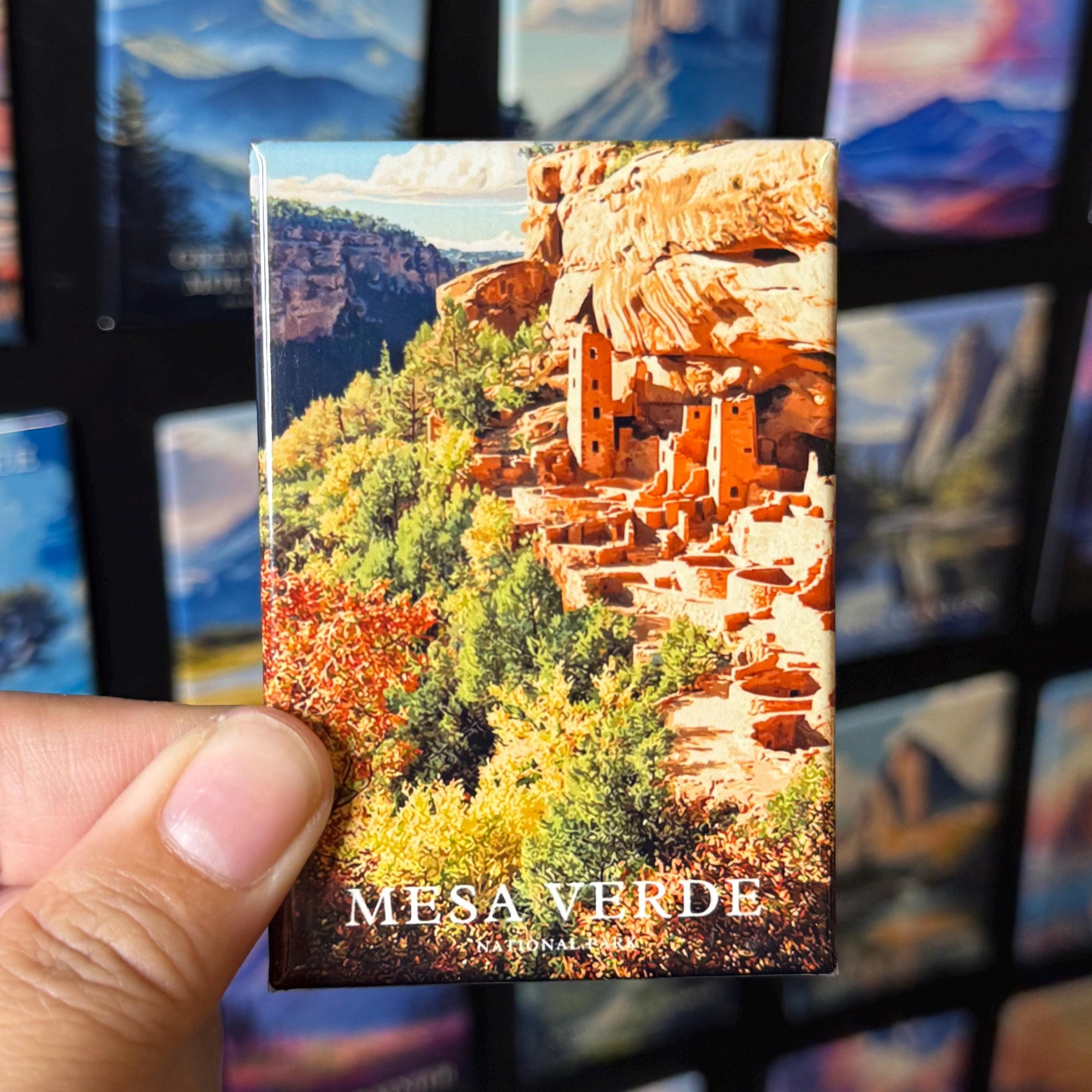 A hand holding a magnet with a picture of the mesa verde, a famous landmark in the Grand Canyon National Park.