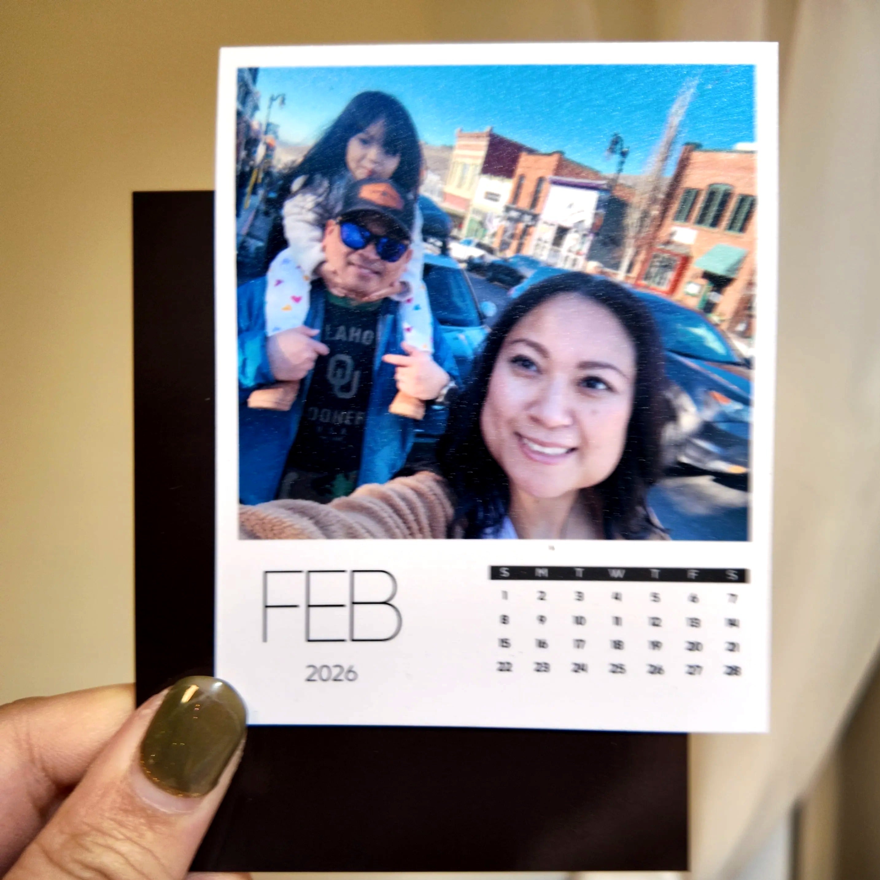A person holding a photo of a family, with a calendar for the month of February visible.