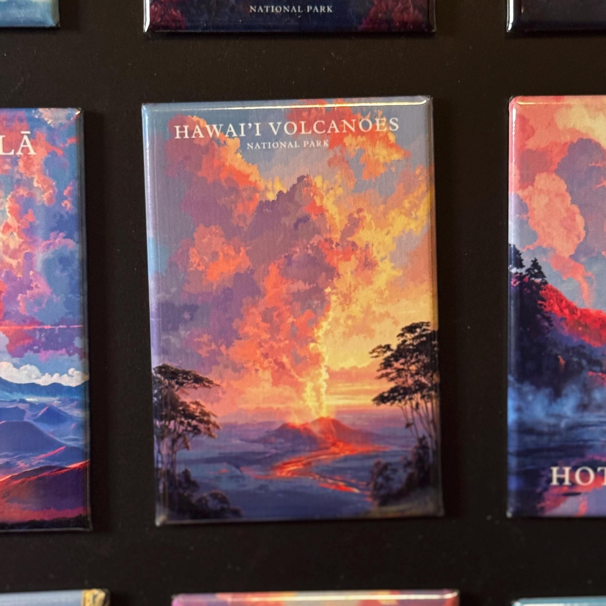 a collection of colorful magnets depicting various scenes, including a landscape with a volcano and a sunset.