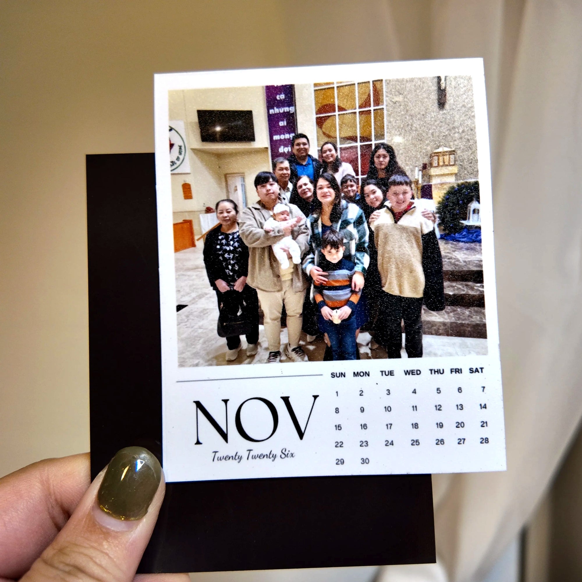A person is holding a small calendar with a photo of a group of people on it.