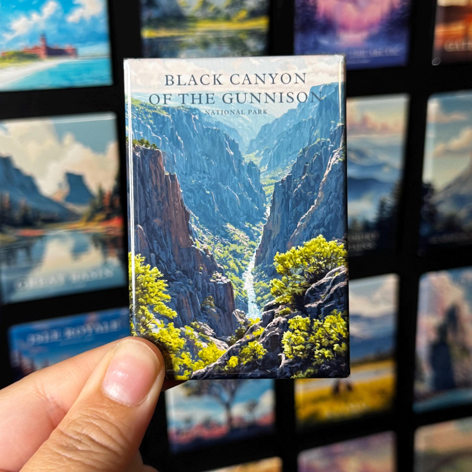 A hand holding a magnet with a picture of the Black Canyon of the Gunnison National Park.