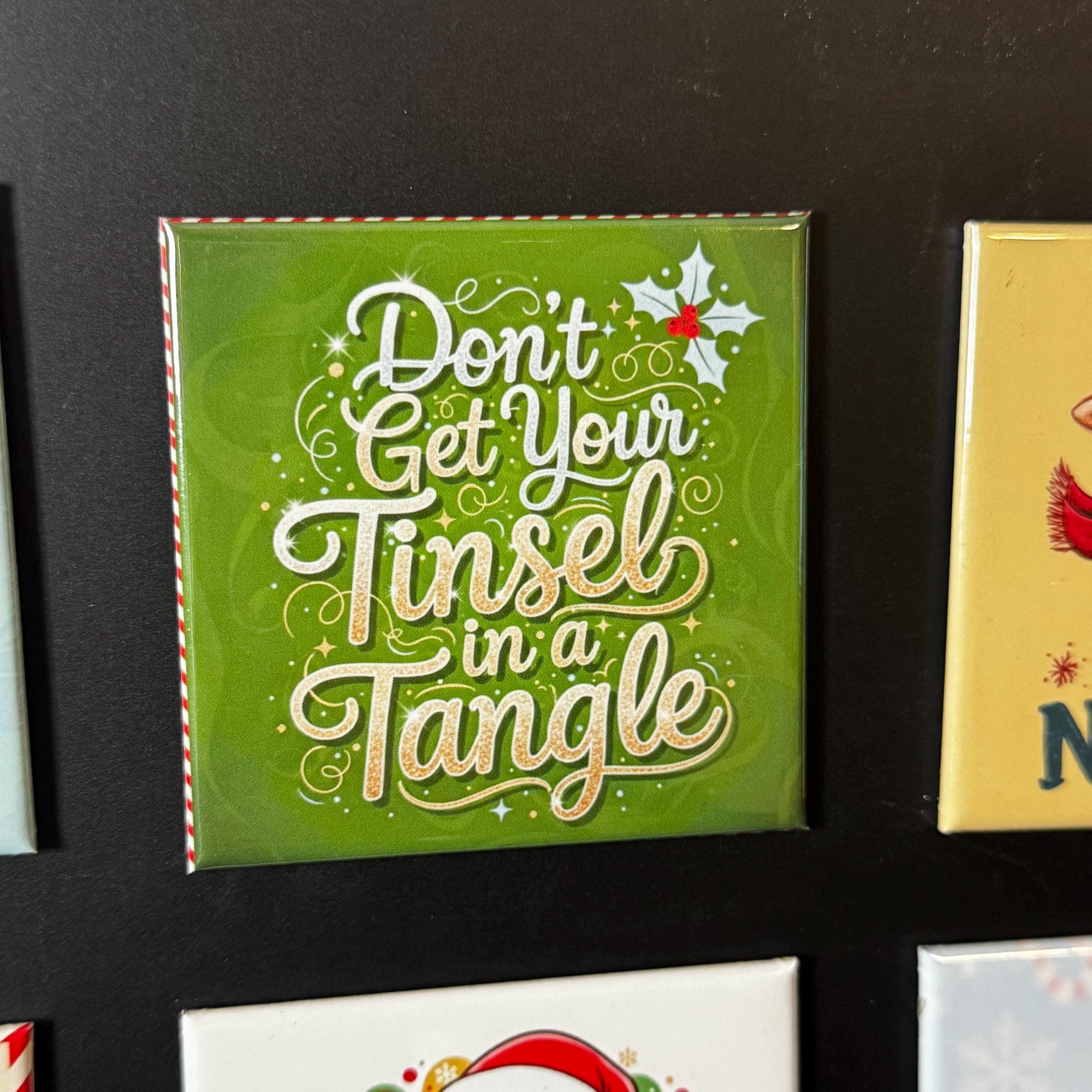 a green square magnet with a decorative text that reads "Don't Get Your Tinsel in a Tangle".