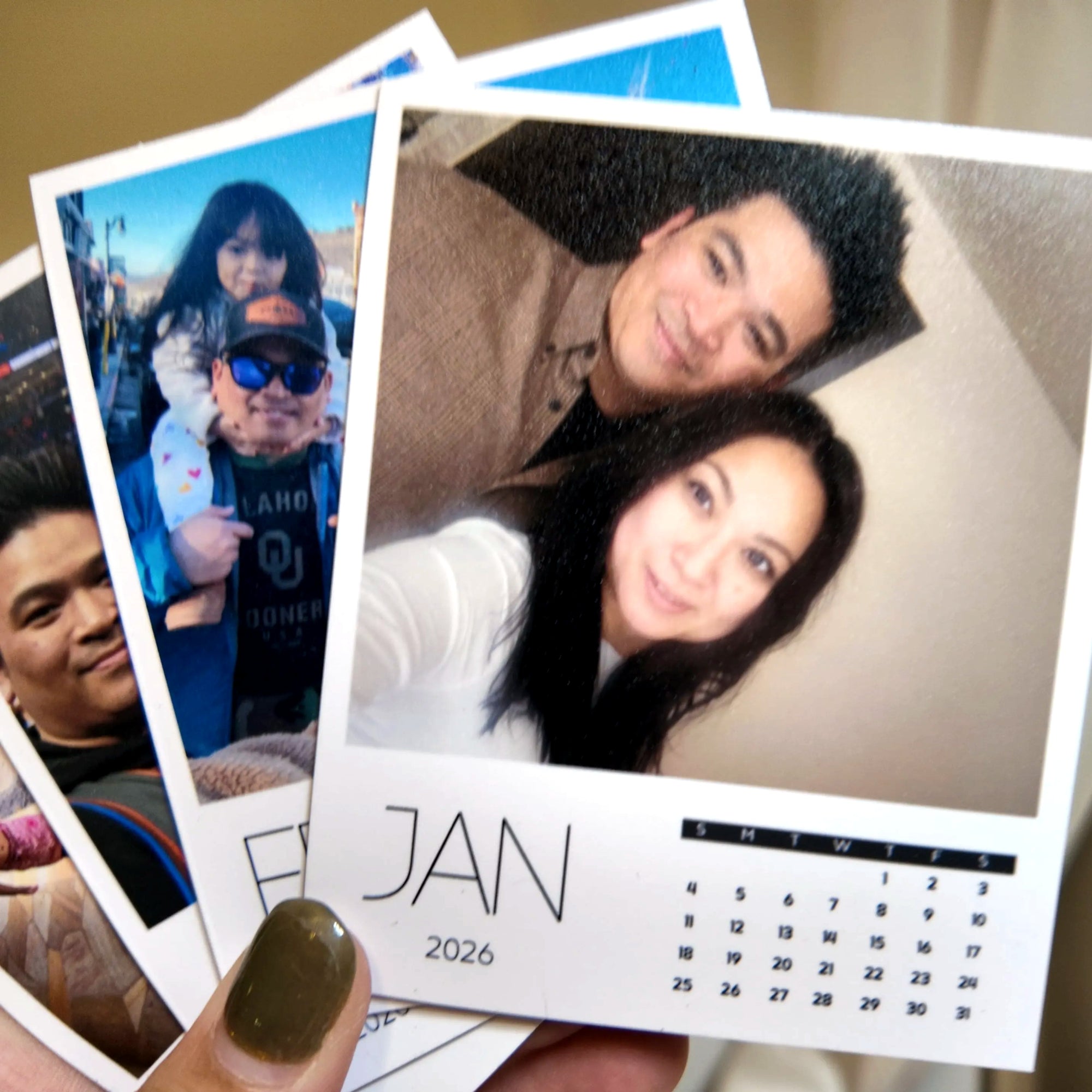 A hand holding a photo album with a couple's photo on the cover, and a calendar for the year 2026.