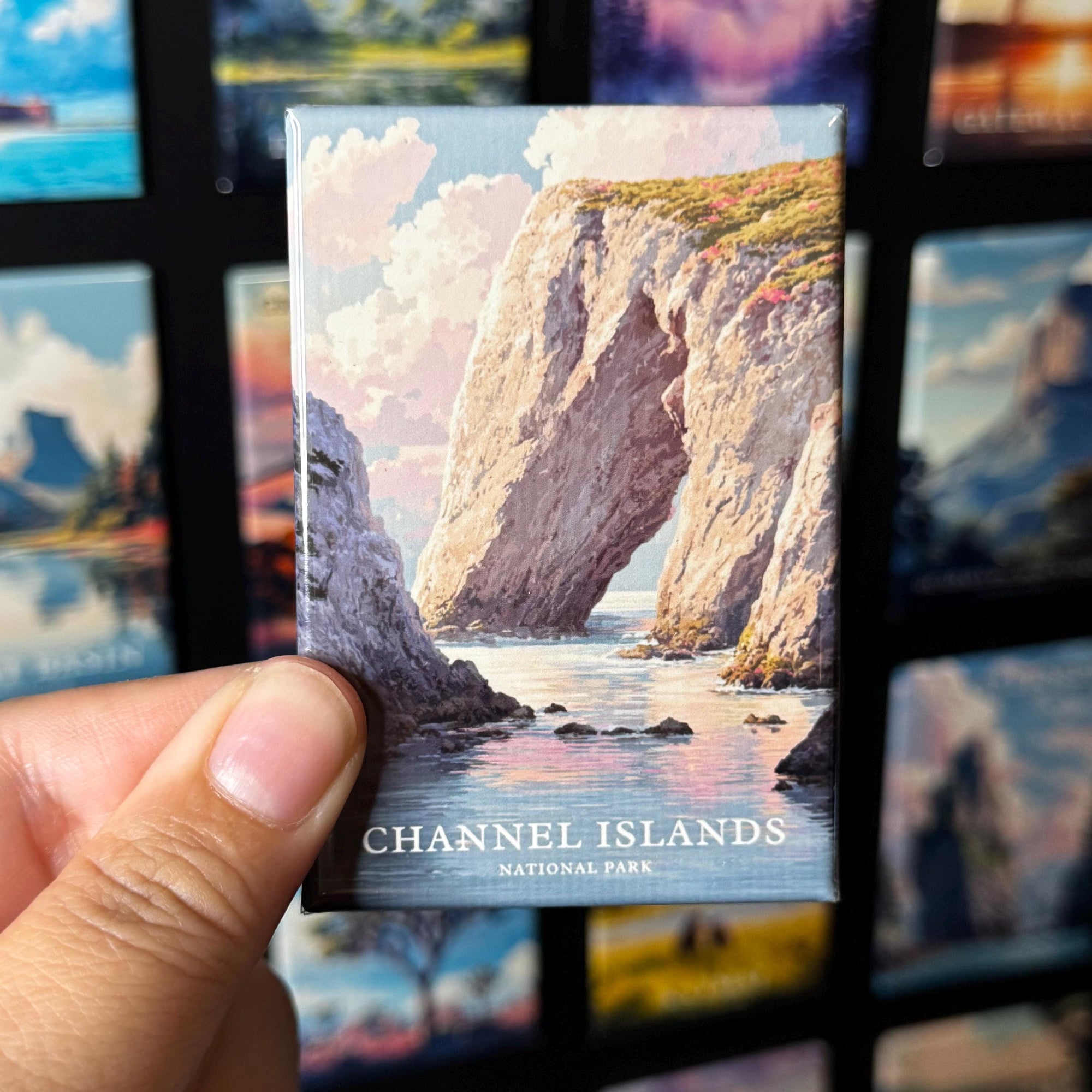 A hand holding a magnet with a picture of a rocky cliff and water in the background, with the text "Channel Islands National Park" visible.