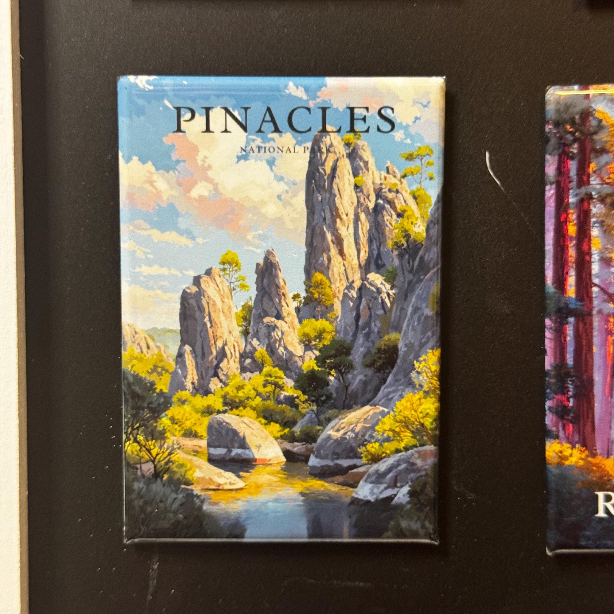 The image is a framed magnet depicting a scenic landscape with a river, mountains, and trees.