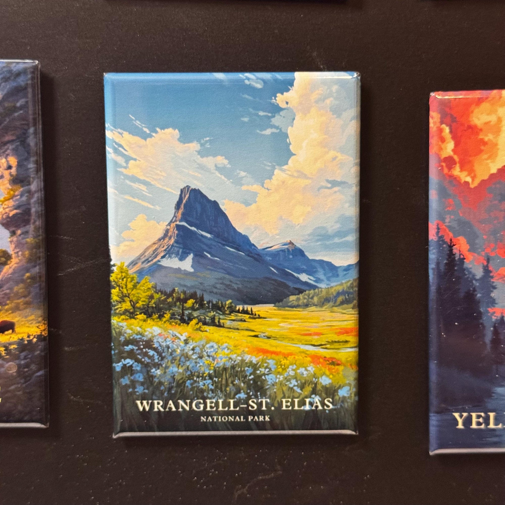 a collage of three landscape paintings, each depicting a different mountain range. The paintings are titled "Wrangell-St. Elias National Park" and are displayed on a black background.