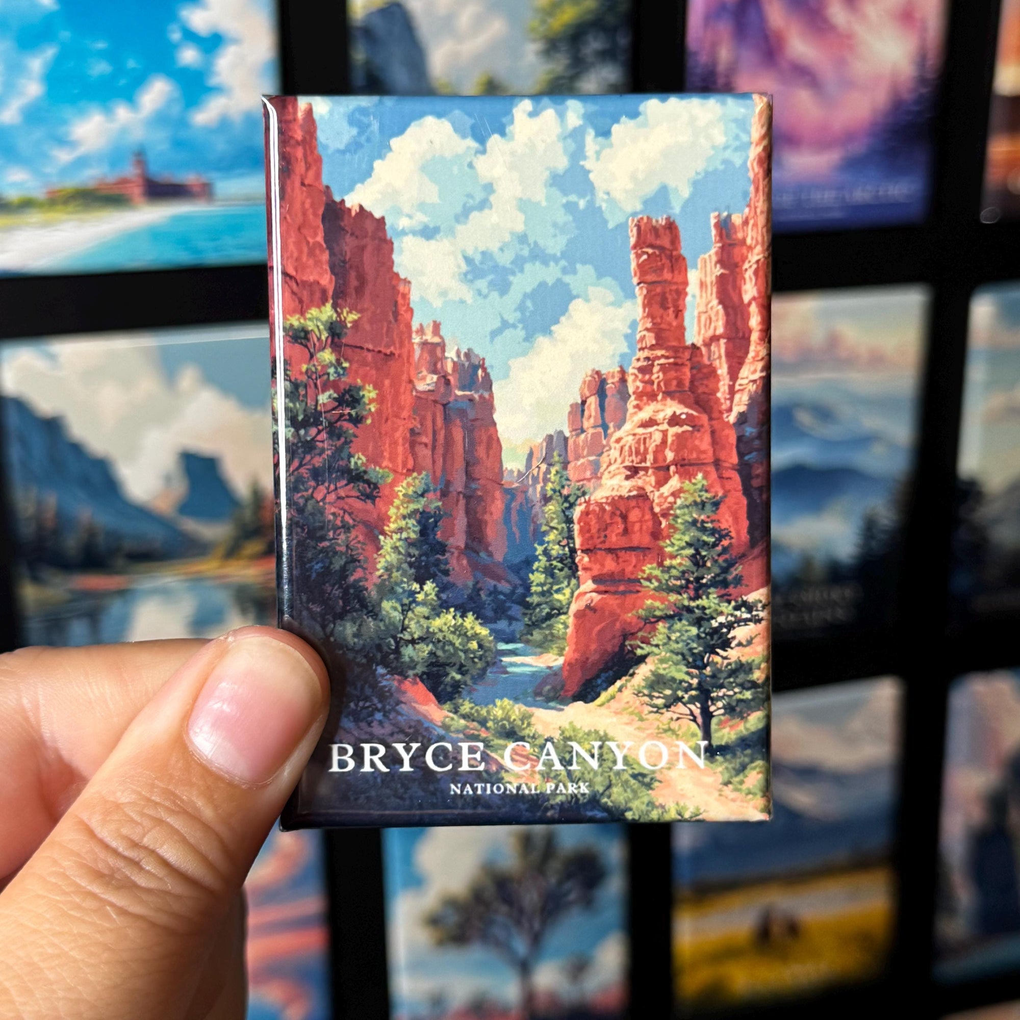 A hand holding a magnet depicting the scenic landscape of Bryce Canyon National Park.