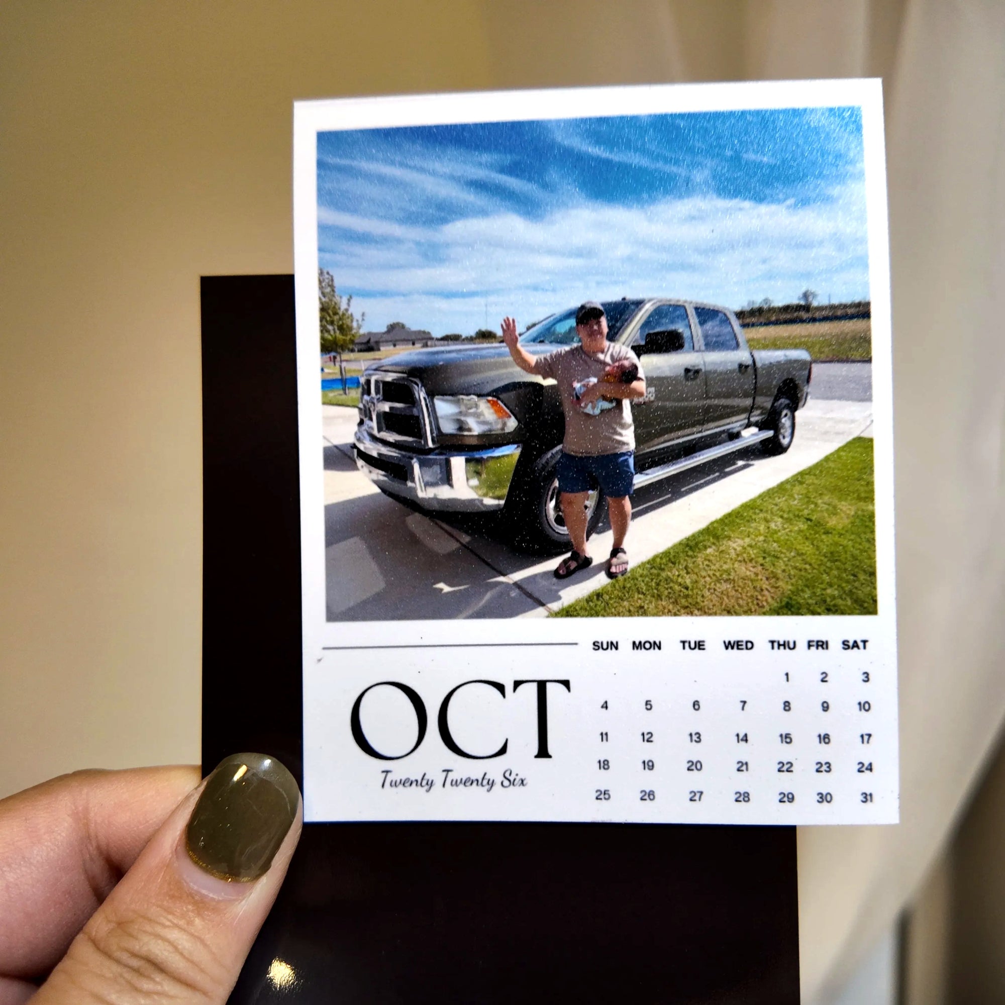 A person holding a calendar card with a photo of a man standing next to a truck.