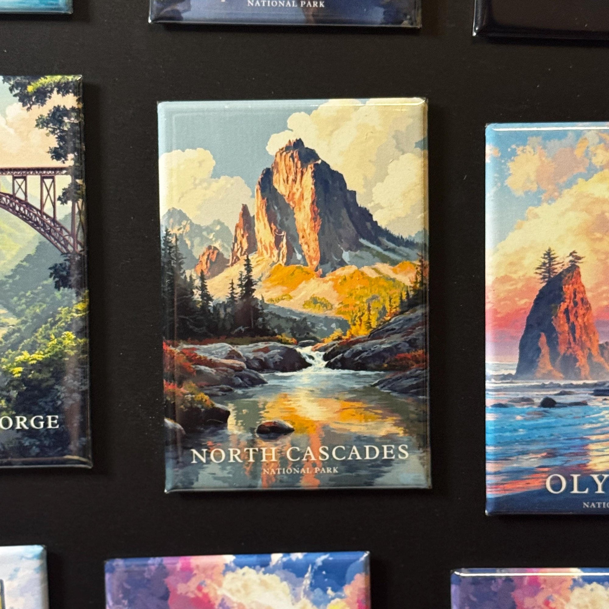 a collection of landscape magnets, each depicting a different scenic natural setting. The magnets feature mountains, water, and various other elements that evoke a sense of nature and adventure.