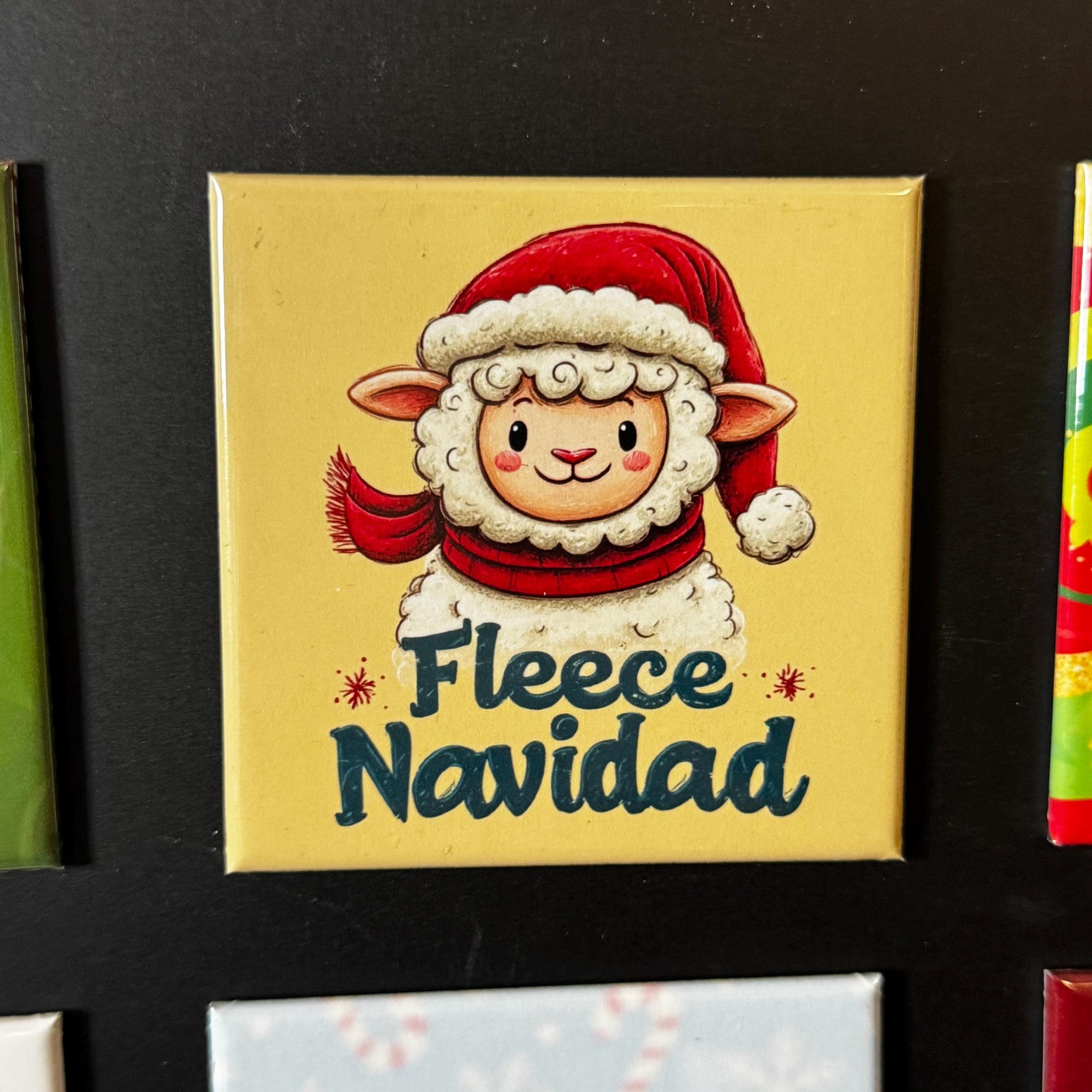 A yellow square magnet with a cartoon image of a sheep wearing a Santa hat and scarf, along with the text "Fleece Navid" written below it.