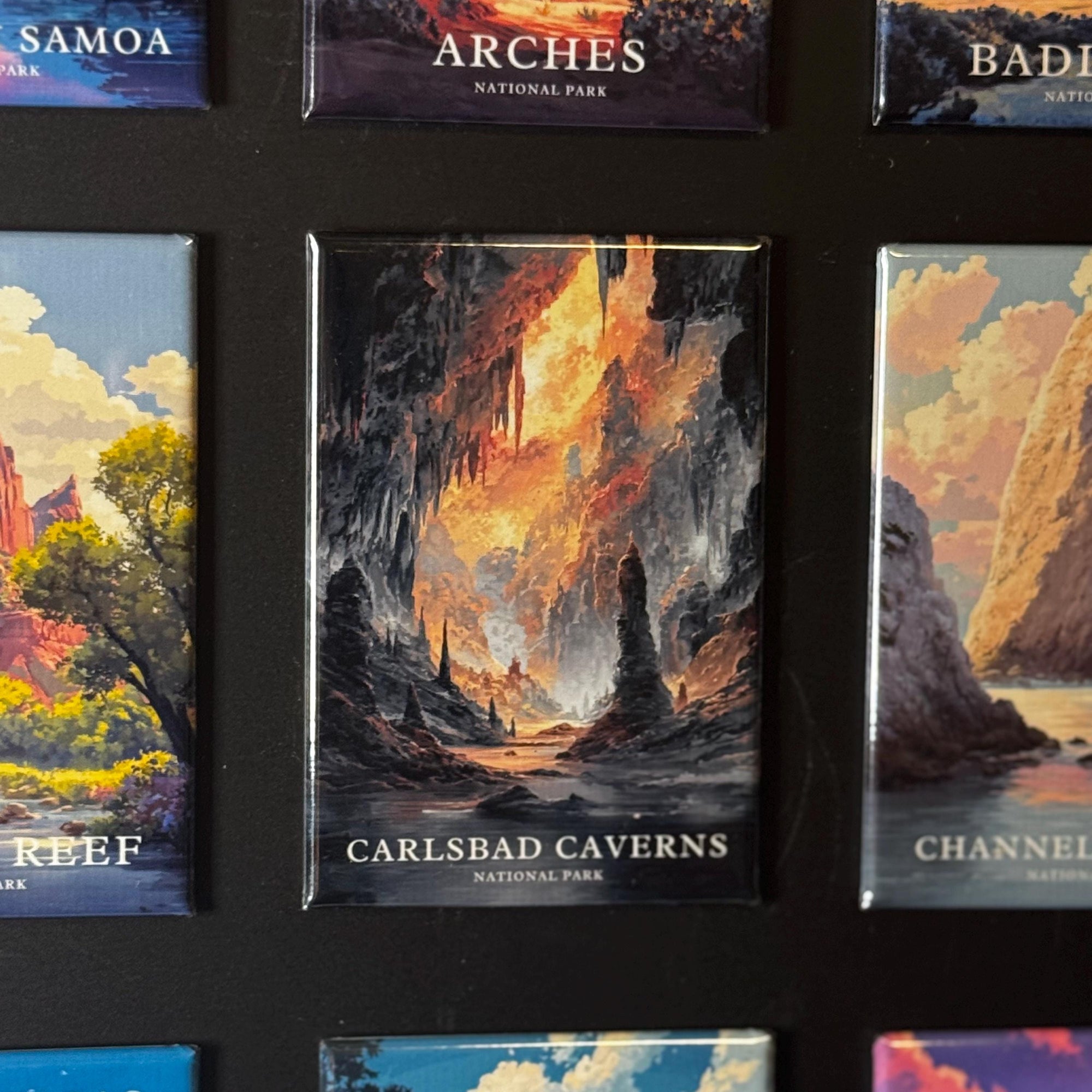 a collection of landscape magnets, each depicting a different natural scene. The magnets are arranged in a grid-like pattern, showcasing various pictures of national parks and natural attractions. The magnets feature a variety of colors and styles, creating a visually appealing display.